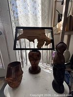 Group shot of two wood vases, carved sculpture and framed wood slab wall art