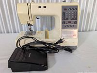 Full view of sewing machine with foot pedal and power cord