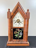 Front view of steeple mantel clock showing full case and floral lower glass