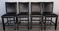 Front view of four matching black faux leather counter stools with nailhead trim