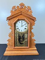 Front view of carved oak Victorian mantel clock showing full case and stenciled glass