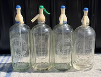 Front view of all four etched glass seltzer bottles