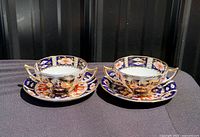 Two Royal Crown Derby Imari soup cup and saucer sets displayed side by side