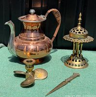 Group shot of copper coffee pot, brass incense burner, candlestick, letter opener