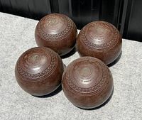 four wooden lawn bowls grouped together on grey surface