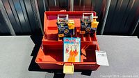 Overall view of open orange tackle box showing both boxed Ocean City reels and hooks card