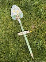 Full view of painted shovel sign laid on grass