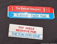 Front view of both metal newspaper box signs showing graphics