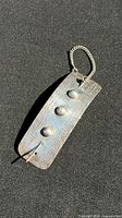 Front view of sterling silver barrette showing three dome studs and attached chain