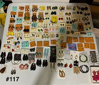 Full layout of approximately 100 pairs of earrings displayed on table