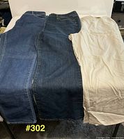 All three pairs laid out: two blue denim, one tan