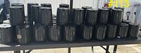 Front view showing three rows of stacked black plastic pots on table