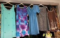 Five dresses hung on hangers showing colors, styles, and condition