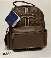Front view of Adrienne Vittadini brown monogram backpack showing horsebit detail, web stripe, front pocket, tags attached