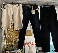 Three garments hung: khaki shorts, dark jeans, black pants all with tags