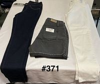 Three pairs of jeans laid flat: dark blue, grey, off-white