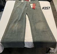 Front view of Levi's Too Superlow jeans laid flat showing full bell bottom legs and waist tags