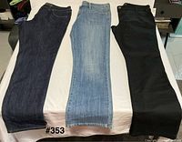 Three pairs of pants laid flat: dark indigo, light blue, black