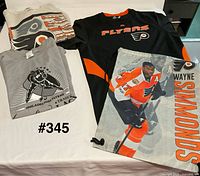 All four items laid out: stained sweatshirt, grey T-shirt, black Adidas shirt, Wayne Simmonds drawstring bag