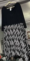Front view of Avenue dress on hanger showing black bodice and geometric skirt