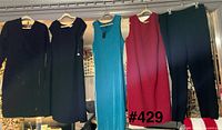 Lineup of four dresses and one pair black pants hanging for full view