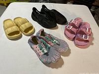 Group shot of all four pairs: yellow slides, black clogs, pink slides, multicolor sneakers