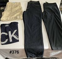 Khaki pants, navy CK tee, dark jeans, black trousers displayed side by side