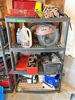 Full view of four-shelf black plastic utility rack with various contents (not included)