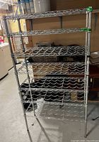 Front view of assembled chrome metal wine rack showing seven wave-pattern bottle shelves