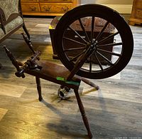 Full view of wood spinning wheel against floor, detached flyer visible