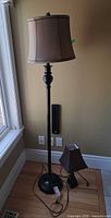 Full view of tall floor lamp with attached drum shade and small table lamp at base