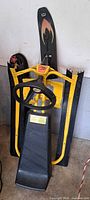 Full view of folded yellow and black GT Sno Racer snow sled showing steering wheel, seat, twin runners
