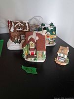 Four miniature resin Christmas village houses on tabletop