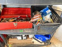 Red toolbox and black crate on shelf containing assorted tools