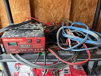 Front and top view MotoMaster charger with attached cables and other lot contents behind