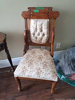 Front view of chair showing carved crest rail, tufted back, floral upholstery and cabriole legs