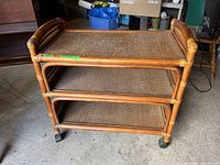 Front three-quarter view of rattan wicker three-shelf serving cart on casters