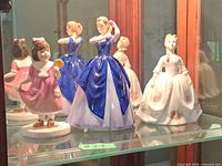 Front view of all three Royal Doulton figurines in display cabinet