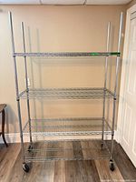 Full view of chrome wire shelving unit showing four shelves and caster wheels