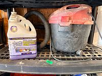 Shop-Vac vacuum next to Simple Green jug on shelf