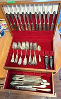Open flatware chest showing knives in lid, forks and shakers in compartment, additional knives in drawer