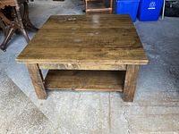 Full view of square solid wood coffee table showing lower shelf and overall form