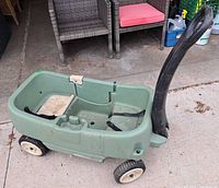 Left side view of Step2 green wagon showing pull handle, wheels, body