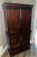 Front view of the armoire showing upper cabinet doors and lower drawer section