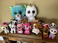 Full group of more than twenty Ty Beanie Boos plush toys on wooden table