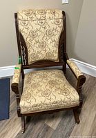 Front view of upholstered rocking armchair showing tufted back, seat, arms, and casters