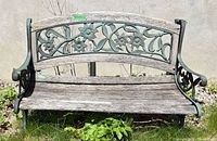 front view of entire bench showing wood slats and cast iron floral backrest