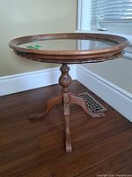 Full view of vintage wood side table with glass top and tripod base