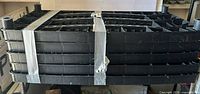 Stacked black plastic shelf panels strapped together