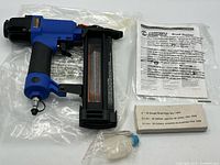 Brad nailer, manual, nails box and oil bottle displayed